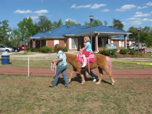 Taylor rides the pink pony at the Magnolia Festival